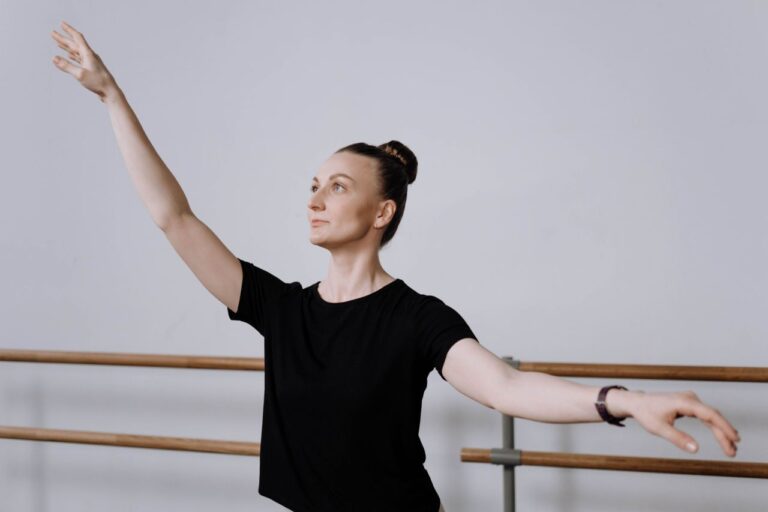A woman practicing ballet in a studio, capturing elegance and focus in a dance pose.